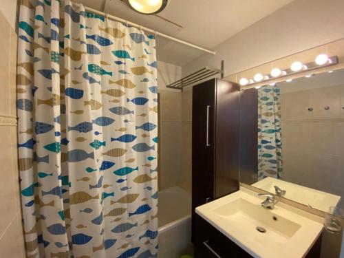une salle de bain avec un lavabo et un rideau de douche dans l'établissement Appartement spacieux à Capbreton avec terrasse, animaux acceptés, parking sécurisé - FR-1-413-253, à Capbreton