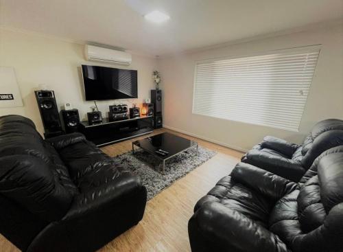 a living room with a leather couch and a flat screen tv at Shore Beats Workin in Esperance
