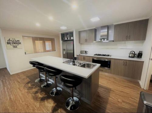 a kitchen with a sink and a counter with bar stools at Shore Beats Workin in Esperance