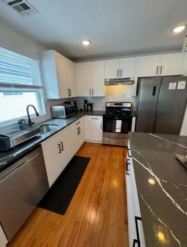 a kitchen with white cabinets and stainless steel appliances at Luxury Gated NYC Theme 3BR 2B with Parking by EWR in Elizabeth