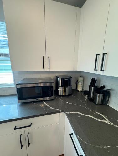 a kitchen with white cabinets and a microwave at Luxury Gated NYC Theme 3BR 2B with Parking by EWR in Elizabeth