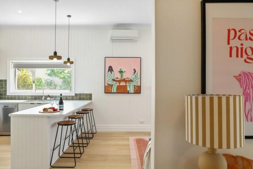 a kitchen with a white counter and bar stools at Wilson House - Central Character Home in Mount Gambier
