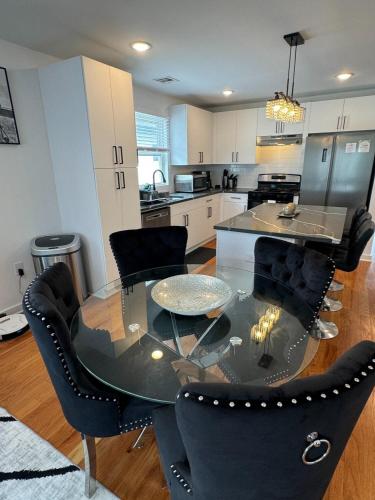 a kitchen with a glass table and black chairs at Luxury Gated NYC Theme 3BR 2B with Parking by EWR in Elizabeth