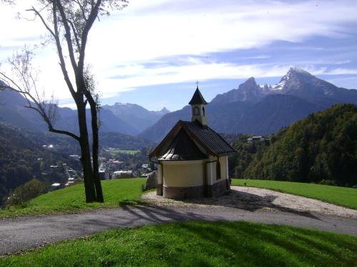 a small chapel on a hill with mountains in the background at Ferienwohnung Wein in Berchtesgaden