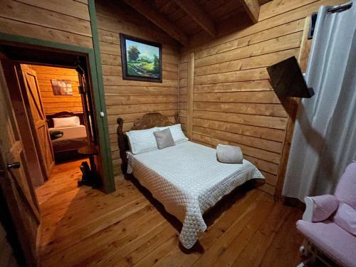 une chambre avec un lit dans une cabane en rondins dans l'établissement Parque Nacional Volcán Poás Cabaña Abby, à Bajos Tigre