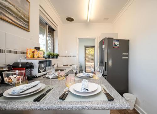 a kitchen with a table with plates and wine glasses at B1 Airport Haven - Free Parking & Modern Serenity in Perth