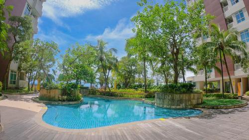 a swimming pool in the middle of a courtyard with trees at Apartment Borneo Bay City - AH Property Indonesia in Balikpapan