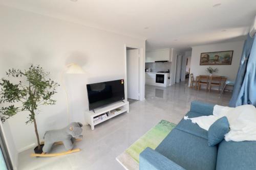 a living room with a blue couch and a tv at A2 Airport 2BR Haven - Garden & Parking in Perth