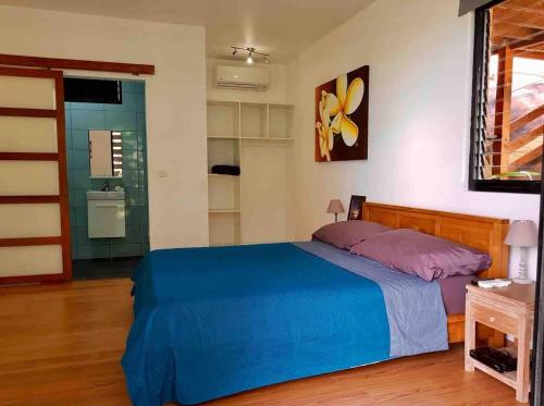 a bedroom with a blue bed in a room at Suite au milieu des arbres in Punaauia