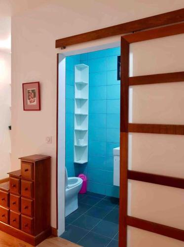 a bathroom with a toilet and a blue wall at Suite au milieu des arbres in Punaauia