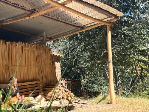 a woman sitting under a wooden pergola at Casita Río Floresta Pisac in Pisac