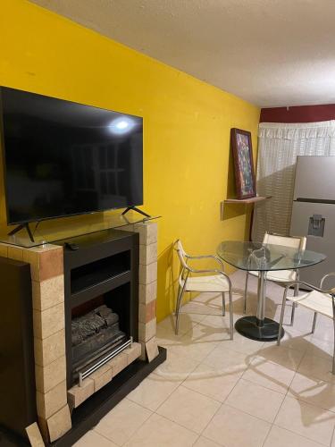 a living room with a fireplace with a flat screen tv at Brisas del Carmen Cercanía y tranquilidad in Celaya