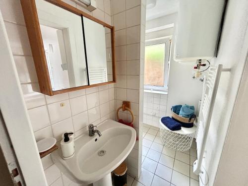 une salle de bain blanche avec un lavabo et un miroir dans l'établissement Appartement au cœur du JARDIN, à Nancy