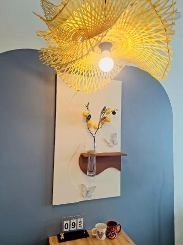 a yellow chandelier hanging over a table with a vase with flowers at TC Apartment & Homestay in An Khê