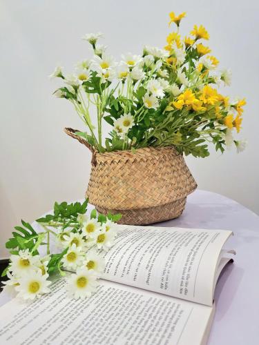 a vase of flowers sitting on top of an open book at TC Apartment & Homestay in An Khê