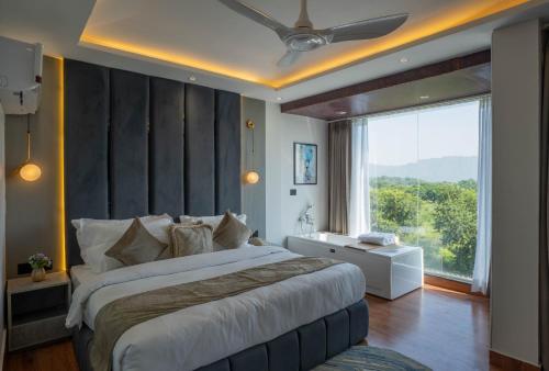 a bedroom with a large bed and a large window at Riverside Bliss at Sukoon - A Riverside Retreat in Haridwār