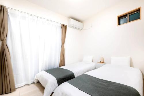 zwei Betten in einem Zimmer mit Fenster in der Unterkunft White Hotel Tsuruhashi in Osaka
