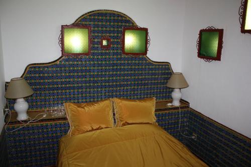 a bed in a room with two lamps and two mirrors at Dar El Mouhit in Sale