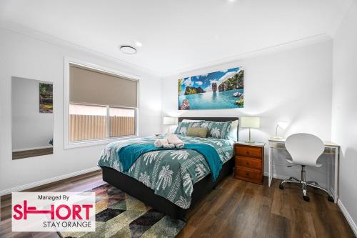a bedroom with a bed and a desk and a chair at Wolaroi Villa 1, with Netflix and Disney Plus in Orange