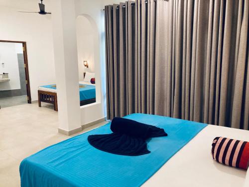 a bedroom with a bed with a blue blanket on it at Seashore Mirissa in Mirissa