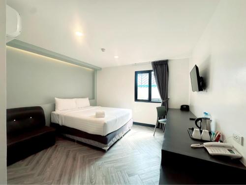 a bedroom with a bed and a couch and a television at 14 Sathorn Hotel No-Parking in Bangkok