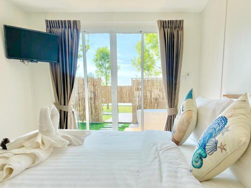 une chambre avec un lit blanc avec une grande fenêtre dans l'établissement Charome Resort, à Ban Suan On