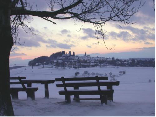 two benches in a snow covered field at sunset at Burghotel Stolpen in Stolpen