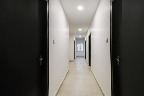 a hallway with white walls and black doors at Super Townhouse Alwal Road in Hyderabad