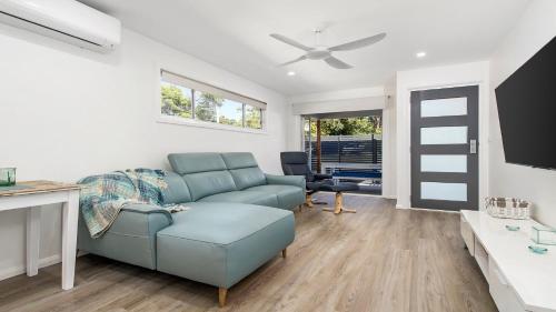 a living room with a blue couch and a ceiling fan at 52a Chalmers Street Flynns Beach in Port Macquarie