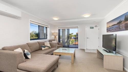 a living room with a couch and a tv at 213 South Pacific Apartments in Port Macquarie