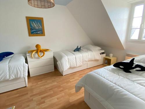 deux lits dans une chambre aux murs blancs et au parquet dans l'établissement Charmante maison à Groix - FR-1-813-19, à Groix