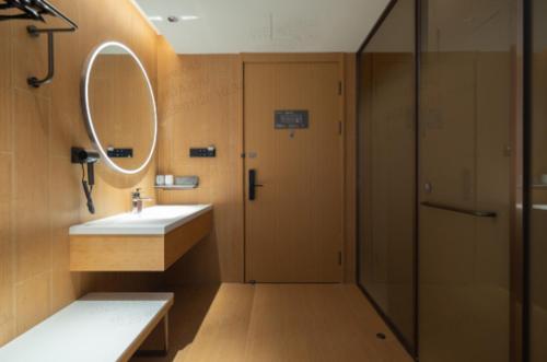 a bathroom with a sink and a mirror and a shower at JI Shanghai International Tourism Liufeng Highway Hotel in Shanghai