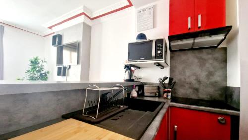 - une cuisine avec un évier et des placards rouges dans l'établissement Bel appartement cosy entier, wi-fi,5min à pied du métro, 15 minutes au coeur de Paris, à Clichy