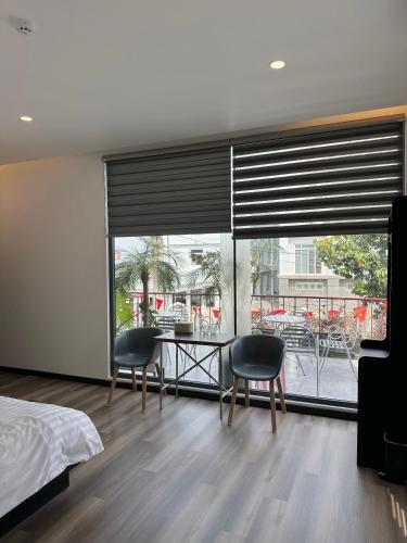 a bedroom with a table and chairs and a large window at Đỏ Đỏ Homestay in Ấp Rạch Mẹo