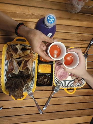 two people holding cups of tea and a sandwich on a table at Ruby House beachside Ocean Hill in La Gi