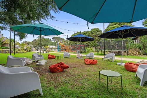 a group of chairs and umbrellas in a park at Tasman Holiday Parks - Papamoa Beach in Papamoa