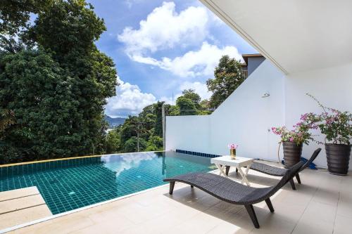 a swimming pool with two chairs and a table on a patio at Private 3-Storey Pool Villa Atika 10, for 7, views of Patong Bay in Patong Beach