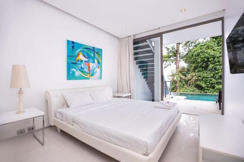 a white bedroom with a bed and a large window at Private 3-Storey Pool Villa Atika 10, for 7, views of Patong Bay in Patong Beach