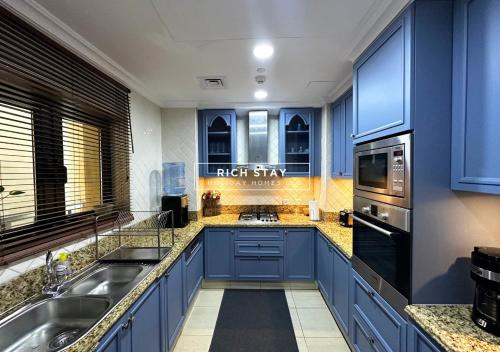 a large kitchen with blue cabinets and appliances at Spectacular 2BR in Souk Al Bahar, Downtown with Burj & Dubai Mall view by Rich Stay in Dubai