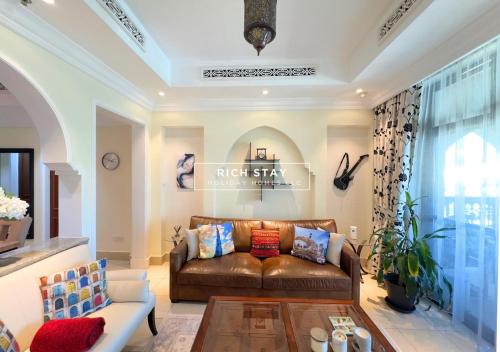 a living room with a brown leather couch at Spectacular 2BR in Souk Al Bahar, Downtown with Burj & Dubai Mall view by Rich Stay in Dubai