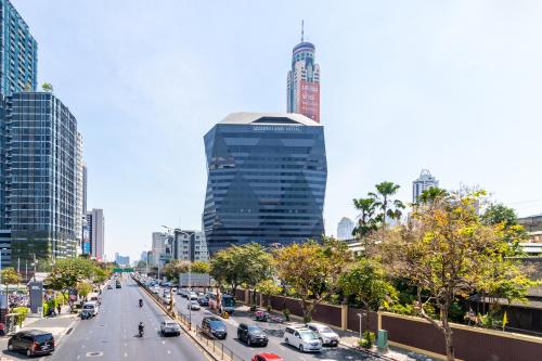 a busy city street filled with traffic with tall buildings at Queensland Hotel Bangkok in Bangkok