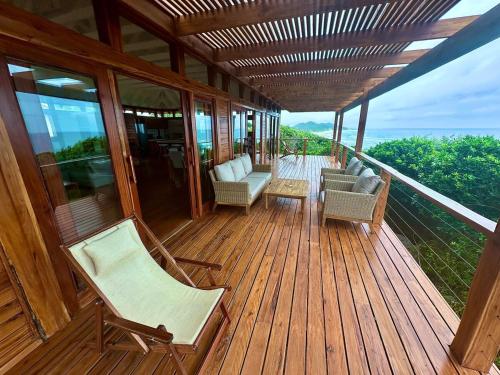 a wooden deck with chairs and a couch on it at Makana 7 in Ponta Mamoli
