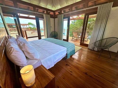 a bedroom with a bed and a balcony with sliding glass doors at Makana 7 in Ponta Mamoli