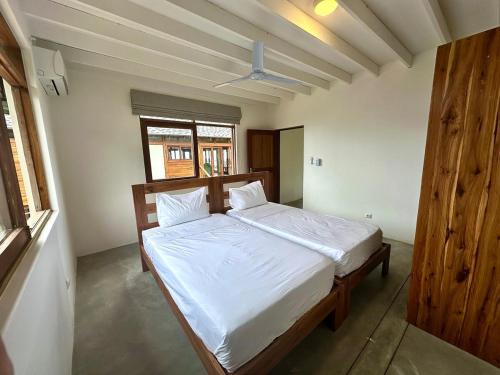 a bedroom with a bed with white sheets and a window at Makana 7 in Ponta Mamoli