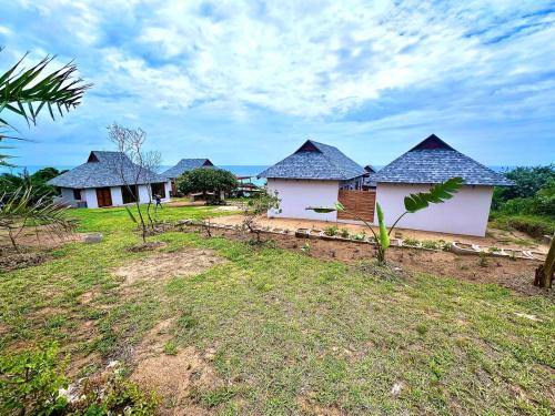 a row of houses with blue roofs in a field at Makana 7 in Ponta Mamoli