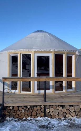 a yurt with windows on a wooden deck at Отдых в комфортабельных юртах в зоне отдыха Kolsay resort! in Kurmenty