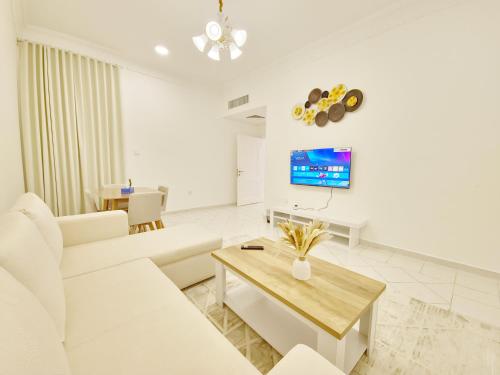a living room with white furniture and a tv at HARF22-101-02 2br apt in AD in Abu Dhabi