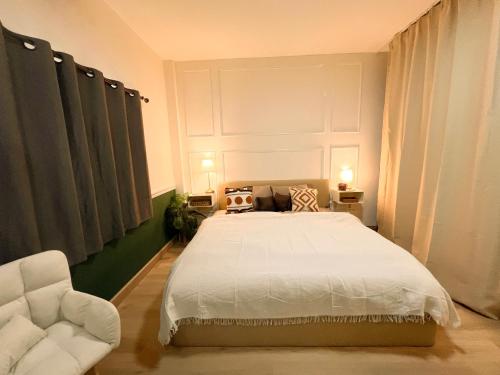 a bedroom with a white bed and a chair at Enjoyo Getaway in Bangkok