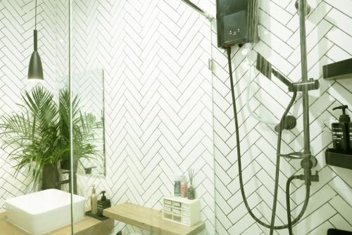 a bathroom with a white tiled wall at Enjoyo Getaway in Bangkok