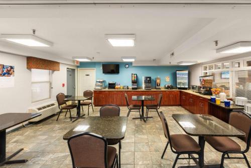 a dining room with tables and chairs and a kitchen at Days Inn by Wyndham Raleigh-Airport-Research Triangle Park in Morrisville